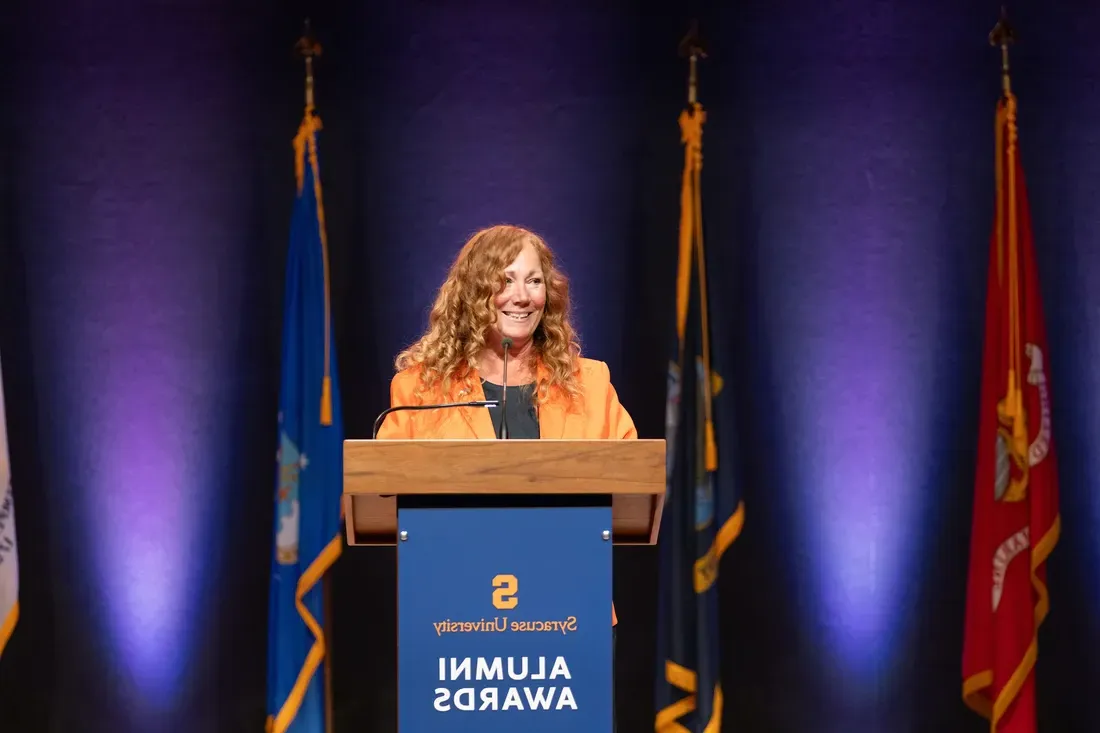 Peggy Combs at a podium speaking.